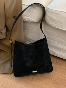 Minimalist black matte shoulder bucket bag with gold hardware shown on a modern background