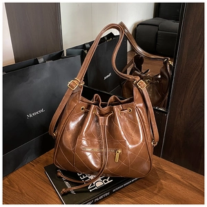 Detail of dark brown quilted leather bucket bag with drawstring closure and zipper pocket