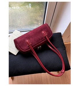 Detailed close-up of retro burgundy Boston bag with contrast white stitching on black cushion