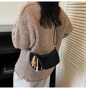 Detail of black suede crescent bag with wooden bead tassel and minimalist strap knot