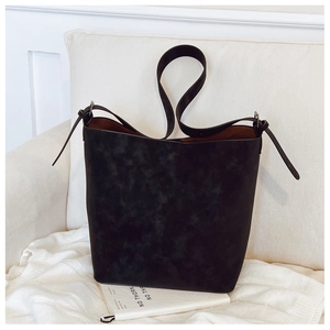 Detail shot of black matte suede bucket bag with decorative knots and wide base strap