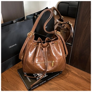 Close-up of retro brown quilted bucket bag with drawstring closure on wooden desk