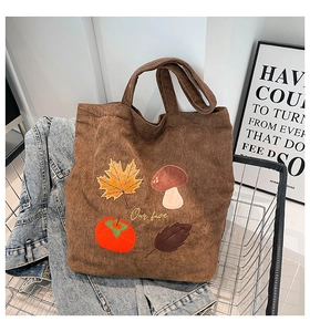 Gros plan sur les broderies d'automne de ce sac cabas en velours côtelé marron