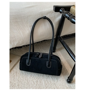 Detail of black suede Boston bag with white contrast stitching on a soft indoor carpet