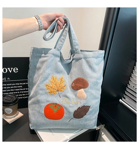 Détail du sac cabas en velours côtelé bleu clair avec broderies de feuilles et champignons