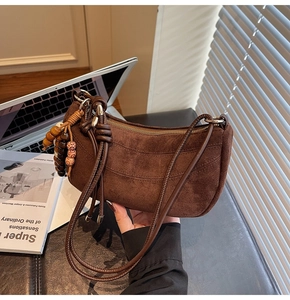 Detail of coffee brown faux suede crescent bag with decorative wooden beads and woven knot