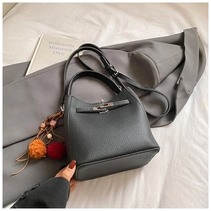 Detail of black lychee grain leather bucket bag with silver twist lock and plush charm