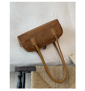 Detail of brown suede baguette bag with light brown leather handles and contrast stitching