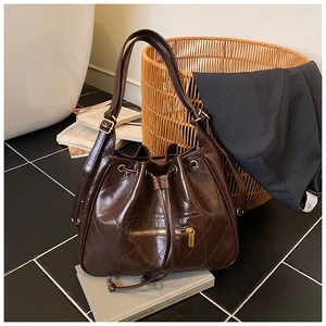 Detail of dark brown quilted leather bucket bag with gold zipper and drawstring closure