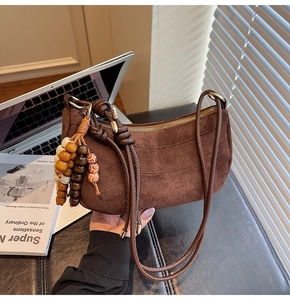 Detail view of a vintage dark brown suede dumpling bag with a multi-colored wood bead charm