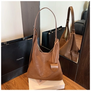 Détail du sac hobo en cuir marron souple avec bandoulière réglable et mini pendentif