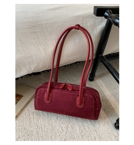 Detailed close-up of dark red suede Boston bag with white contrast stitching and zippers