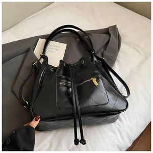 Detailed shot of a black quilted bucket bag with a drawstring closure and gold zipper pocket