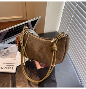 Detailed close-up of brown suede half-moon bag featuring a vintage beaded charm and wood ring