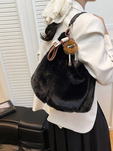 Grand sac cabas en fausse fourrure noire avec pendentif porté par un mannequin chic