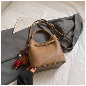 Top view of brown lychee grain leather bucket bag with silver clasp and plush charm