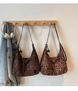 Detail of leopard print hobo bags with tassels hanging on a wooden hook in a cozy setting