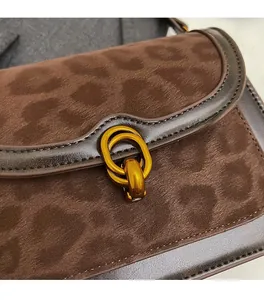 Dettaglio della texture scamosciata leopardata e fibbia dorata su borsa a tracolla marrone