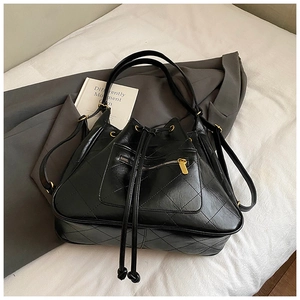 Close-up of black quilted bucket bag featuring drawstring closure and gold hardware