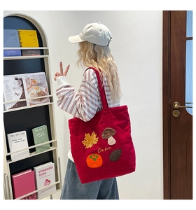 Détail d'un sac cabas en velours côtelé rouge avec broderies de feuilles d'automne