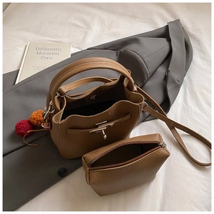 Close-up of brown litchi pattern bucket bag with detachable strap and plush charm