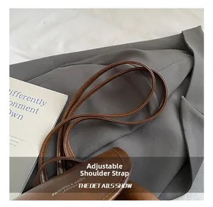 Detail view of the adjustable long shoulder strap on a brown leather vintage backpack