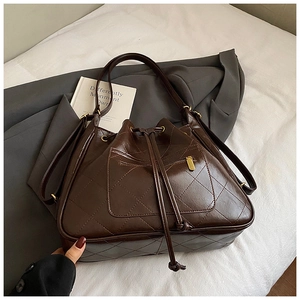 Detail of dark brown quilted bucket bag with golden zipper pocket and drawstring closure