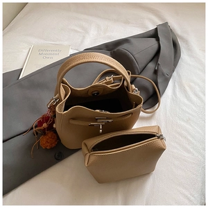 Detailed view of khaki bucket bag with lychee grain leather and plush ball charm accessory