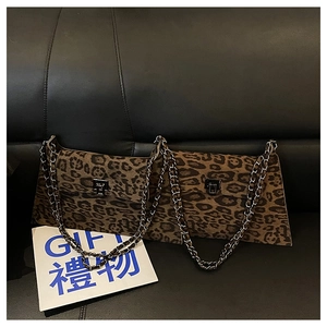 Detail of leopard print crossbody bag with silver metal chain strap on leather sofa