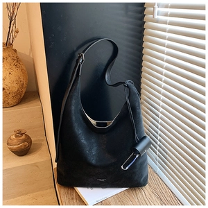 Gros plan d'un sac cabas noir en cuir mat vintage avec petit charm sur une surface en bois