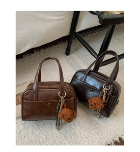 Detail of vintage Boston handbags with plush dog charms on a soft white carpet