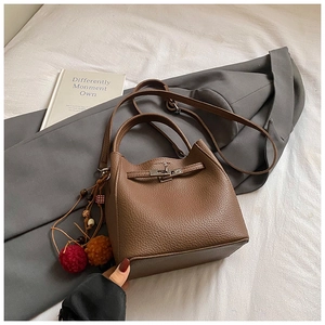 Close-up of brown pebbled leather bucket bag with metallic twist lock and ethnic charm