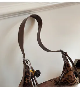 Detail of leopard print tote bag with brown leather strap and silver metal ring