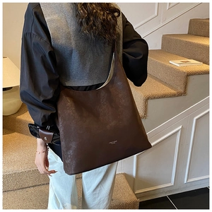 Detail shot of vintage dark brown faux leather tote bag with white logo on stairs