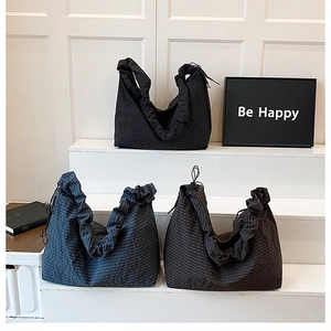 Detailed view of checkered pleat tote bags in black, navy, and dark coffee on steps