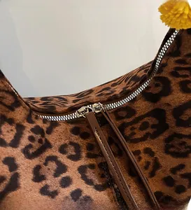 Macro shot of smooth metal double zippers and leather pullers on leopard print tote bag