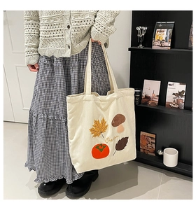 Détail de motifs automnaux brodés sur un sac cabas en velours côtelé blanc cassé