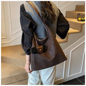 Vue latérale du grand sac cabas en cuir marron foncé avec bandoulière sur l'escalier