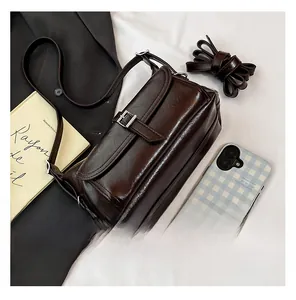 Detail of dark brown leather crossbody bag with silver buckle and adjustable strap
