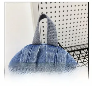 Detail of reinforced gray webbing handle on blue denim backpack for school travel