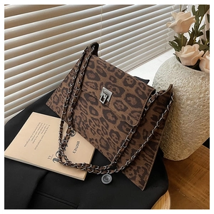 Detail of leopard print flap bag with silver twist lock and chain strap on a black blazer