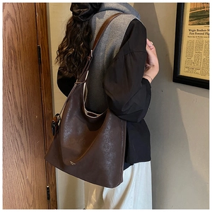 Détail d'un sac cabas vintage en cuir marron foncé avec logo doré et bandoulière large