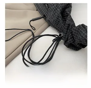 Detailed close-up of the black checkered fabric and thin drawstring cord of the tote bag