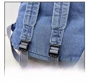 Detail of adjustable shoulder strap and plastic buckle on denim backpack for students