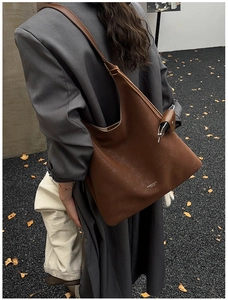 Sac hobo vintage marron porté avec un costume gris dans un décor d'automne
