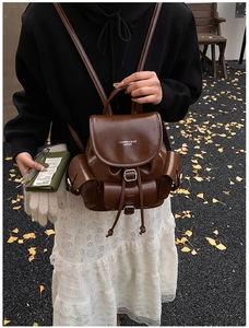 Detailed view of brown matte leather backpack with flap buckle and side pockets