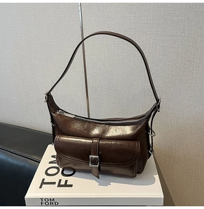 Detail of dark brown glossy leather shoulder bag with silver zipper on fashion books
