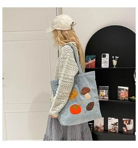 Détail de la broderie d'automne avec feuilles colorées sur un sac cabas en velours côtelé