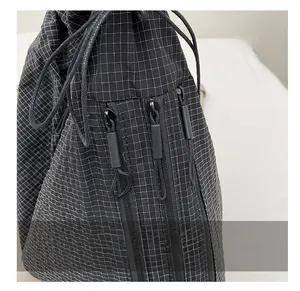 Detail shot of the black checkered nylon bag with smooth zippers and drawstring closure