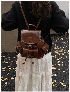 Brown faux leather backpack featured in an autumn street scene with ginkgo leaves